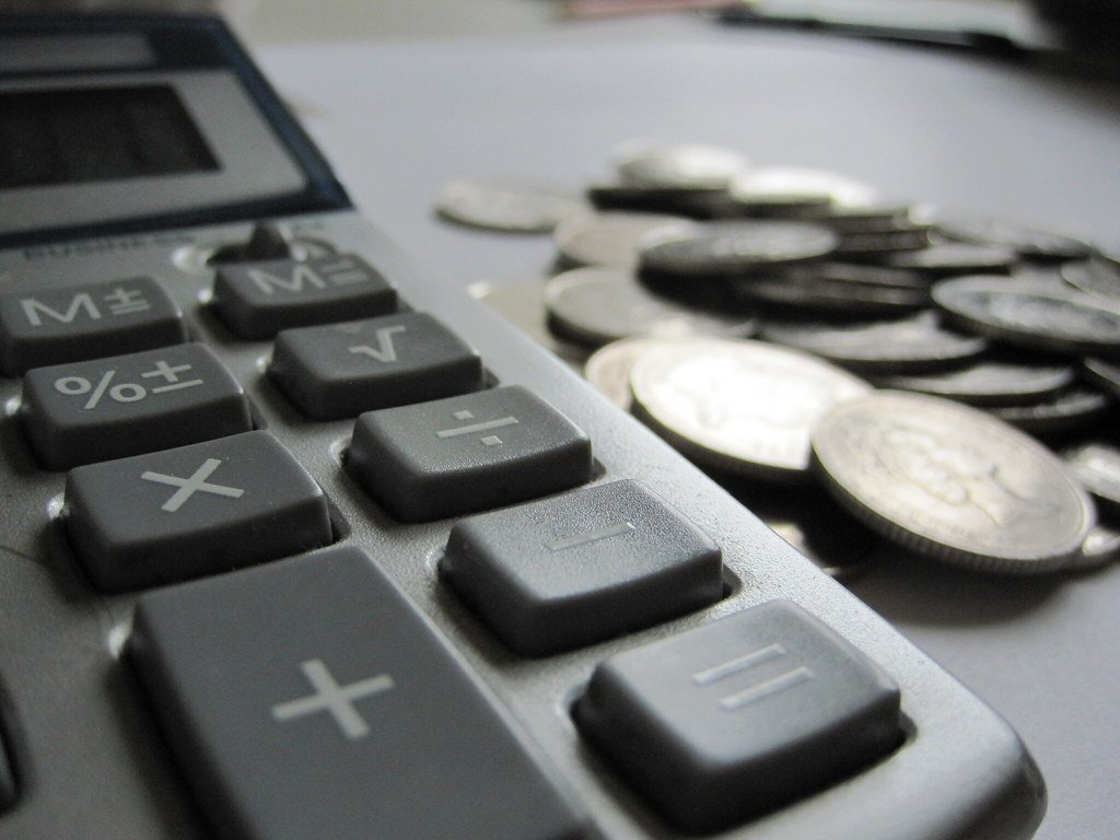 Calculatrice posée sur des billets, illustrant le calcul des frais d'un contrat d'assurance vie.