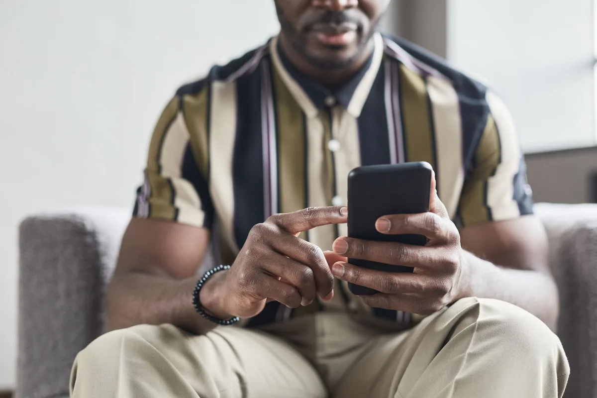 Une personne tient un smartphone affichant une application bancaire ouverte sur un écran de virement